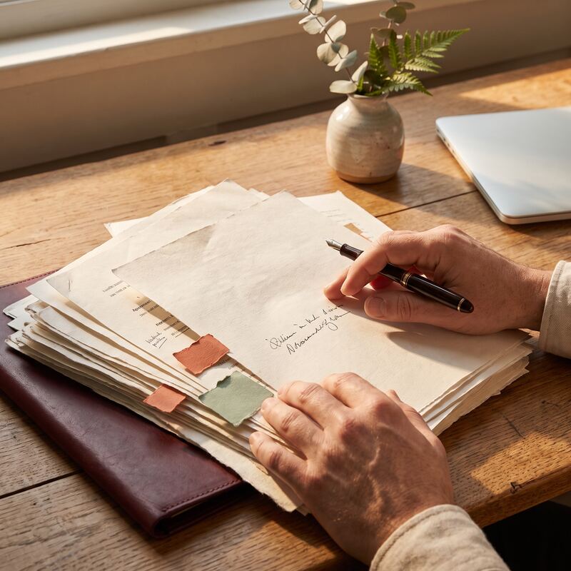 Close-up of a lawyer's hands annotating tabbed contract pages during AI-assisted document review in an Australian law firm