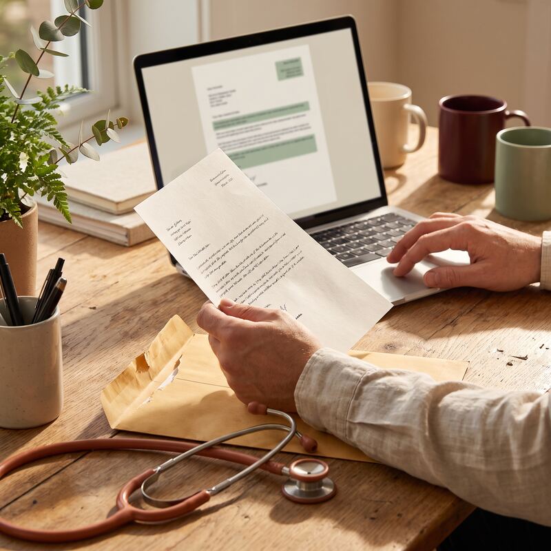 Close-up of a doctor's hands checking an AI-drafted referral letter beside a laptop in an Australian medical practice Close-up of a doctor's hands checking an AI-drafted referral letter beside a laptop in an Australian medical practice