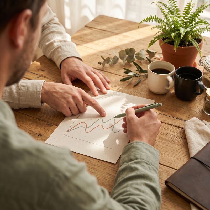 Two marketers comparing paid and organic search trend charts on paper, coordinating PPC and SEO strategy for AI Overviews Two marketers comparing paid and organic search trend charts on paper, coordinating PPC and SEO strategy for AI Overviews