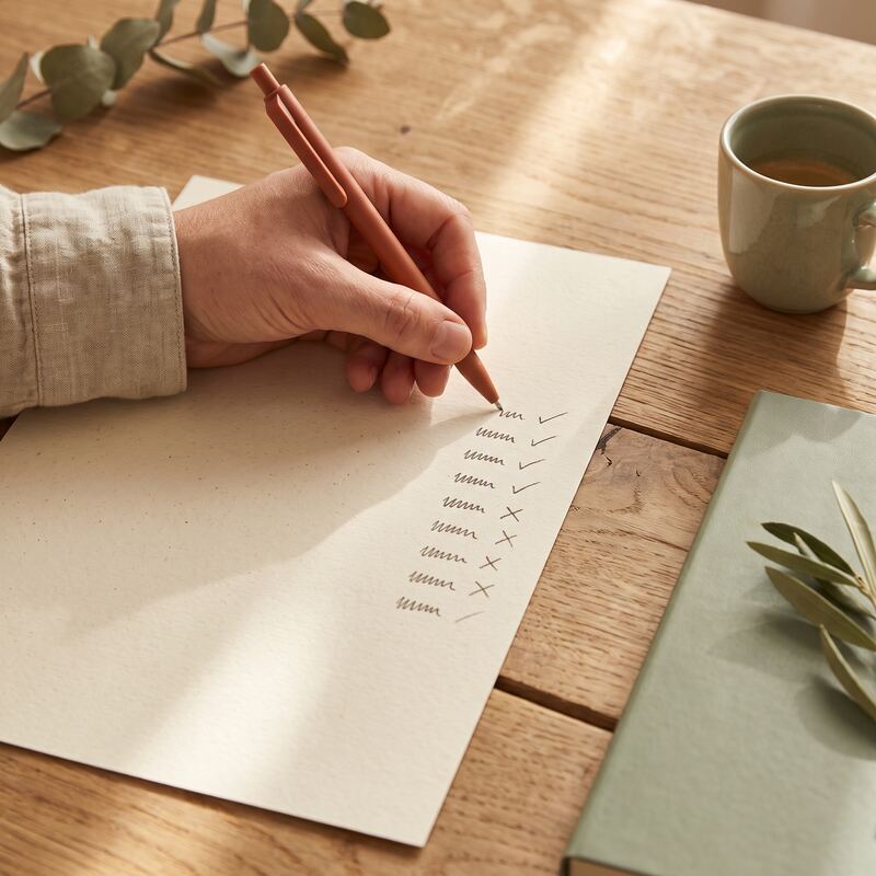 Hand reviewing a printed search terms report with terracotta ticks and crosses, essential upkeep for broad match keywords