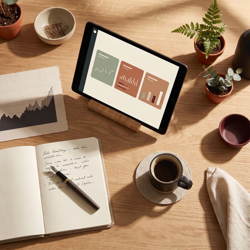 Overhead desk with tablet marketing dashboard, printed performance charts and notebook for a daily review routine Overhead desk with tablet marketing dashboard, printed performance charts and notebook for a daily review routine