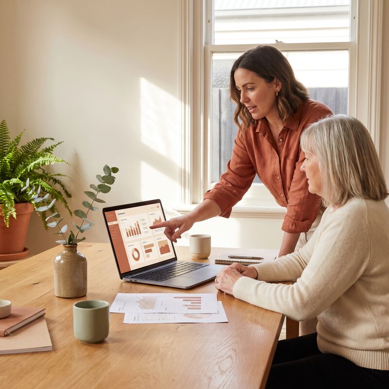 Marketing consultant walking a business owner through AI discovery optimisation on a warm-toned dashboard