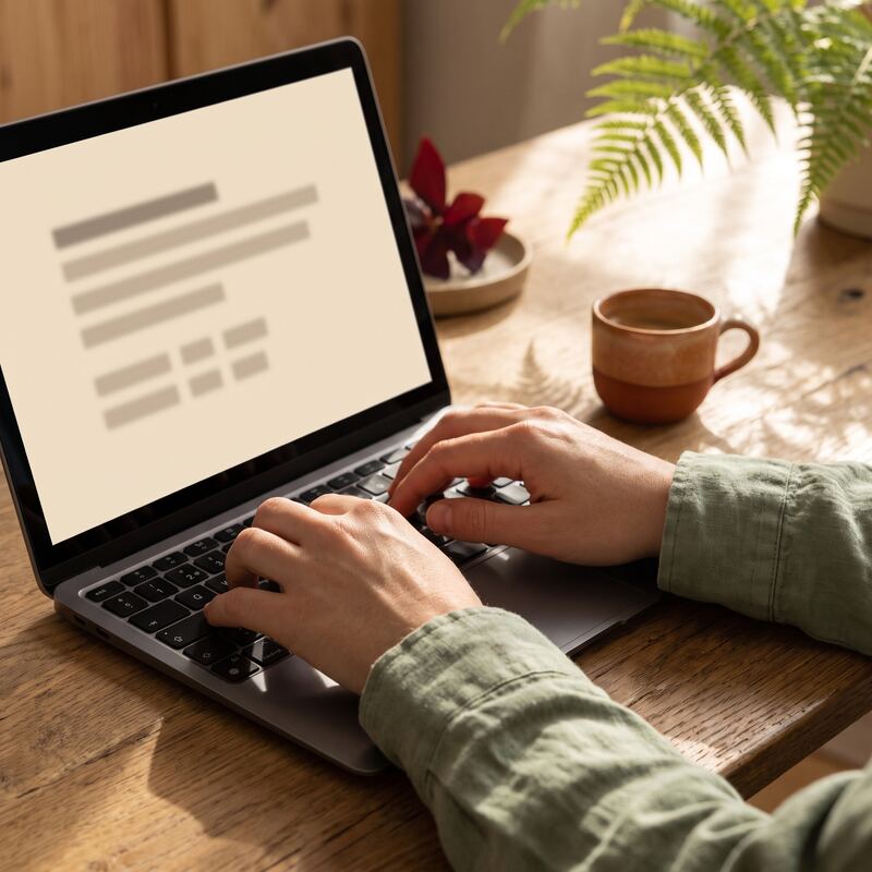 Hands typing a question-and-answer structured blog post on a laptop with warm cream interface in golden window light Hands typing a question-and-answer structured blog post on a laptop with warm cream interface in golden window light