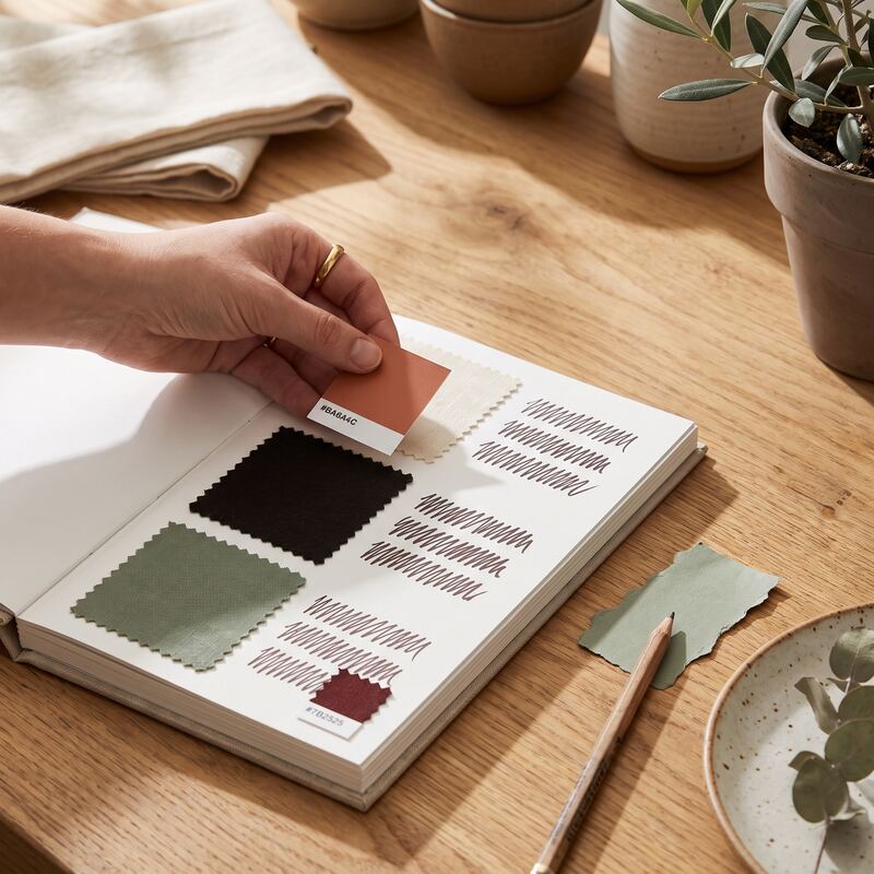 Hand matching terracotta and sage colour swatches to a printed style reference page defining brand image rules Hand matching terracotta and sage colour swatches to a printed style reference page defining brand image rules